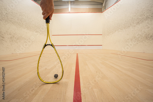 Obraz na plátně Male hand holding a racket inside a squash court
