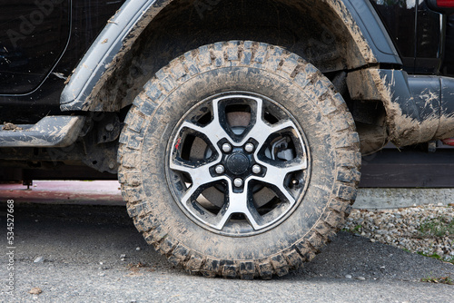 Dried mud on SUV's off-road mud tires. Close up low angle view, no people