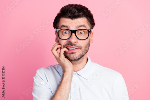 Closeup photo of young funny attractive handsome cute guy wear lenses bad vision nervous bite nails driving test problems isolated on bright pink color background photo