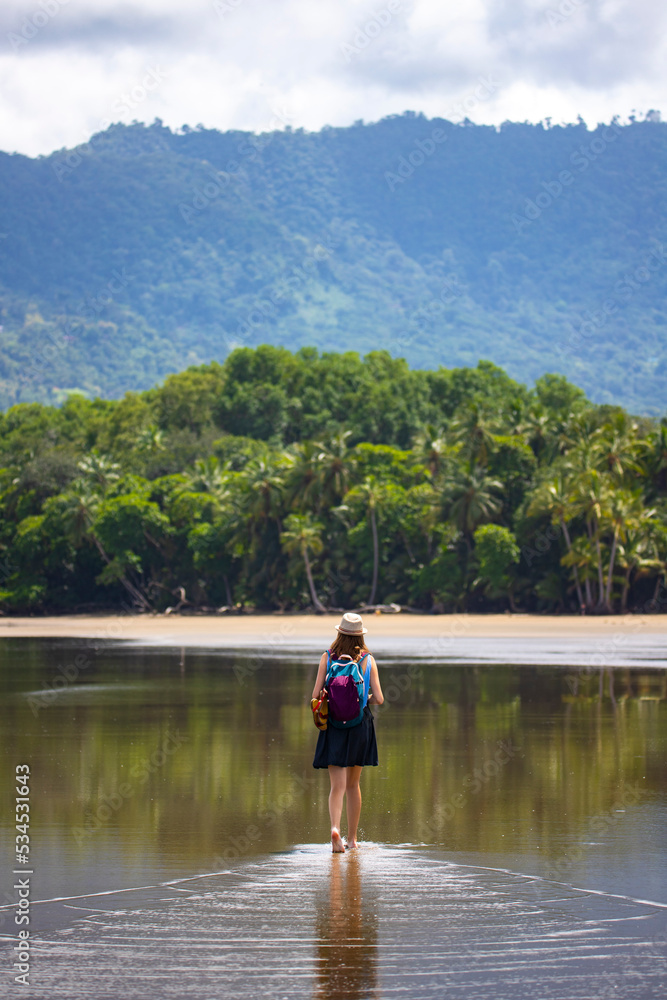beautiful girl enjoying walk on the tropical beach with palm trees in the background; sunny day on the beach in costa rica; marino ballena national park