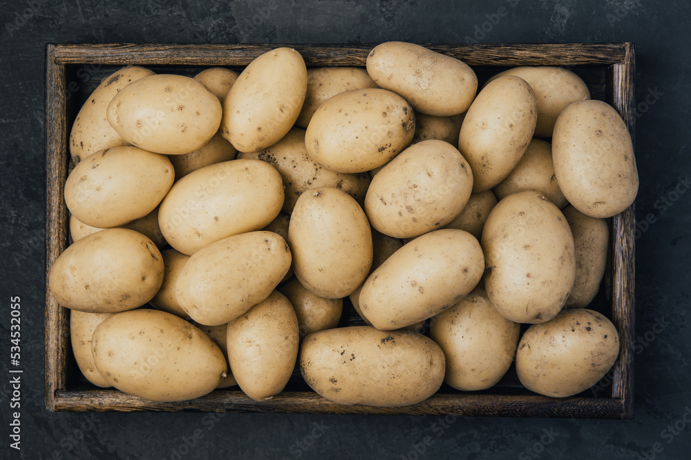 Potato. Fresh raw organic potatoes in wooden box on dark stone background. Potato. Fresh raw organic potatoes in wooden box on dark stone background.