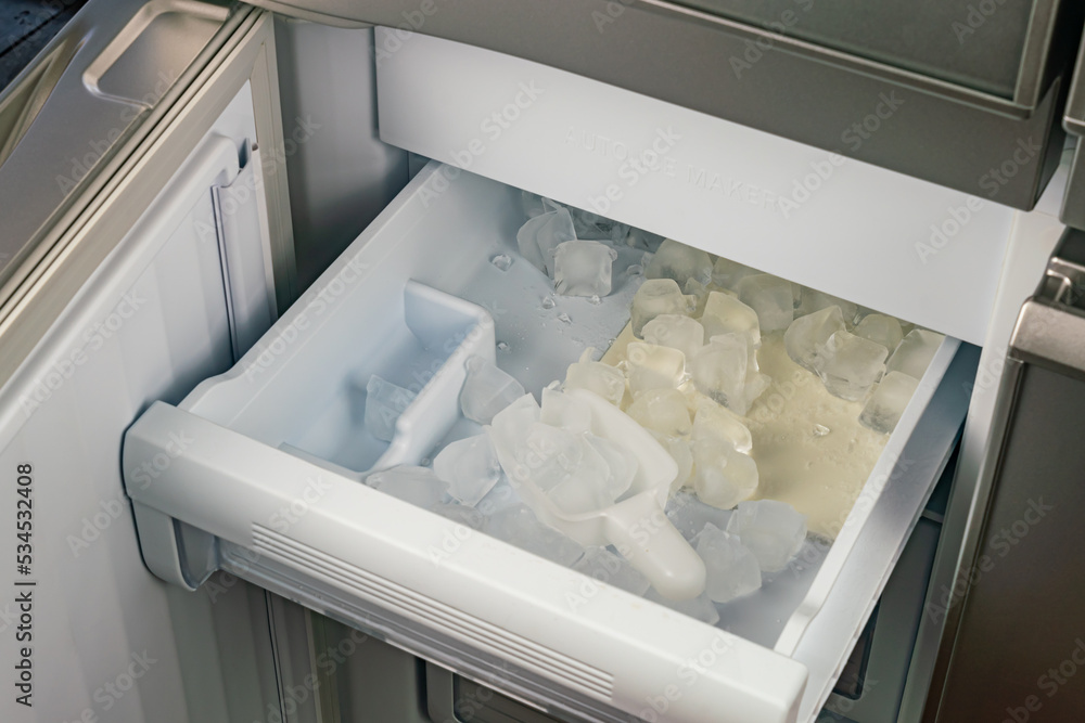 Inside of automatic ice maker with a drawer of ice cubes and plastic