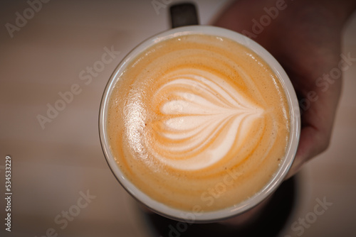 Cup of coffee soya latte art and coffee beans on old wooden background