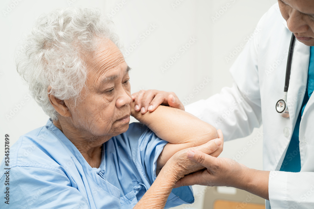 Obraz premium Asian senior or elderly old lady woman patient feel pain her elbow on bed in nursing hospital ward, healthy strong medical concept.