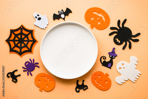 Halloween food concept. White plate, cobweb, hands, spiders, pumpkins. Flat lay image with copy space.