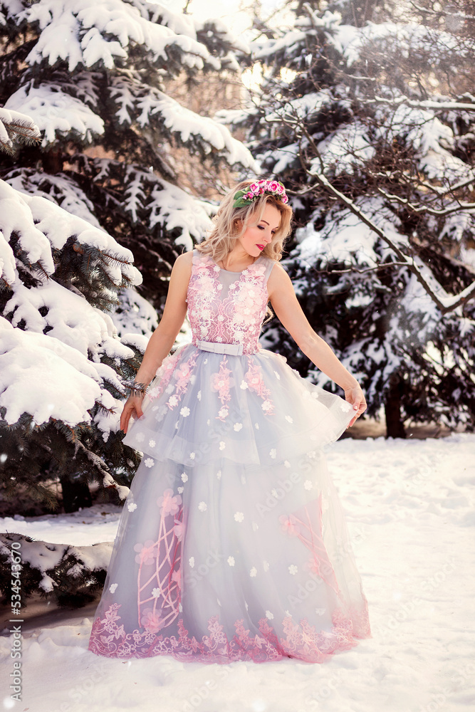 Beautiful woman in a luxurious blue fairy-tale dress in a snowy forest Beautiful woman in a luxurious blue fairy-tale dress in a snowy forest