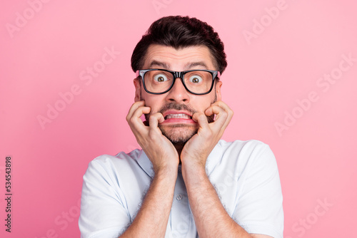 Closeup photo of young funnny handsome attractive bearded man bite fingers nails nervous face wear glasses deadline work manager isolated on pink color background