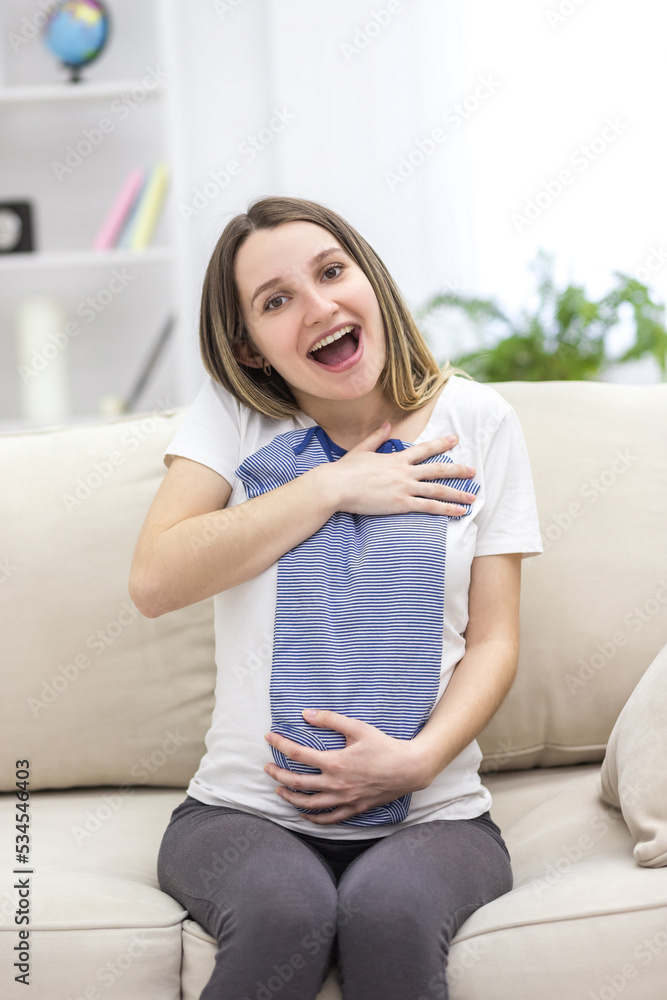 Photo of pregnant woman wearing casual clothes and holding childish clothes in hands. Photo of pregnant woman wearing casual clothes and holding childish clothes in hands.