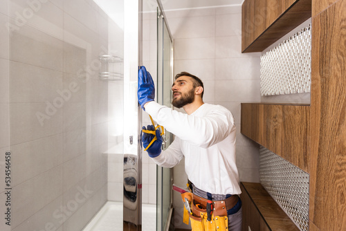 Professional plumber with plunger and instruments near sink.