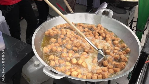 slow motion of chef is frying tofu in a large skillet. photo