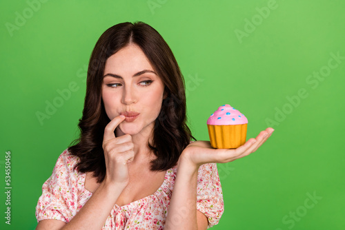 Closeup photo of young pretty gorgeous nice woman wear pink top bite finger hold tasty yummy cake delicious muffin isolated on green color background