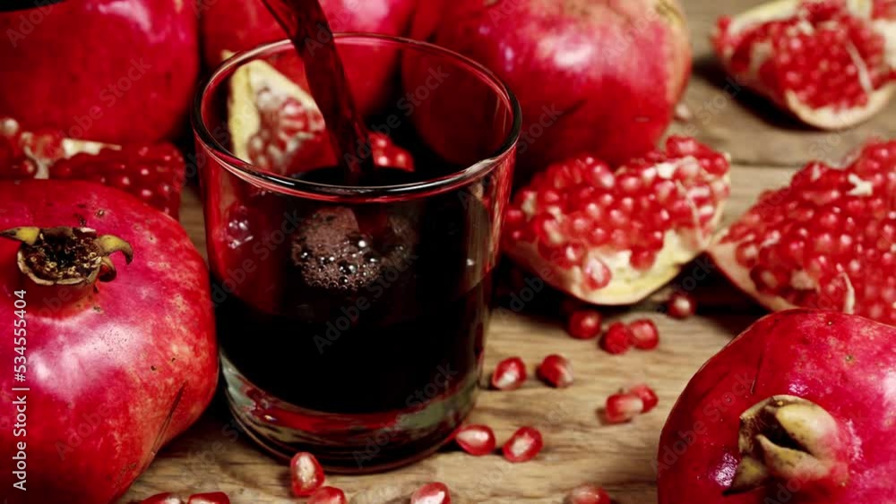 pouring pomegranate juice into glass surrounded by pomegranates, real time pouring pomegranate juice into glass surrounded by pomegranates, real time