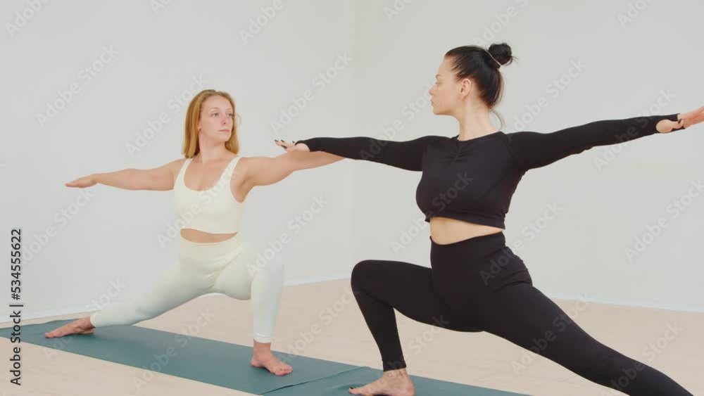 Close-up of two young women practicing partner yoga and stretching on a mat Close-up of two young women practicing partner yoga and stretching on a mat