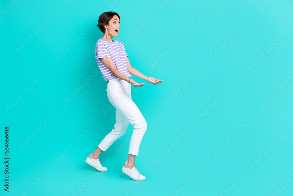 Photo of pretty impressed girl dressed purple t-shirt holding amrs looking empty space isolated teal color background Photo of pretty impressed girl dressed purple t-shirt holding amrs looking empty space isolated teal color background