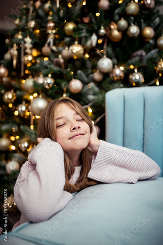 Cute teenage girl in a room with a decorated Christmas tree. The winter holidays. © murika
