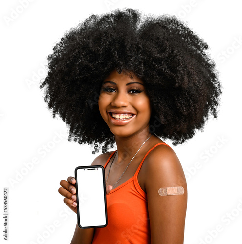 black girl without face shield holds the cell phone close to her arm with the vaccine sticker, fully immunized, chroma key on the cell phone screen, looking at camera