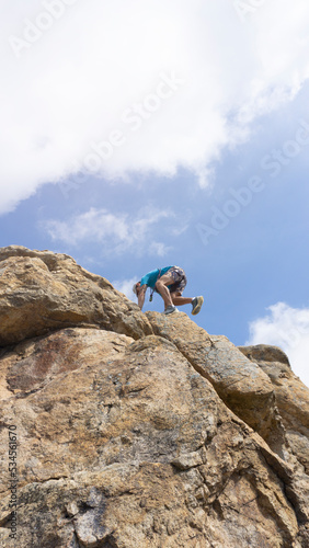 low view of man climbing on rock with blue sky in background . copy space