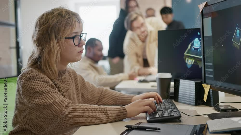 Caucasian female artist designer in glasses draws 3D model for a computer game in the office of a project development studio. Caucasian female artist designer in glasses draws 3D model for a computer game in the office of a project development studio.