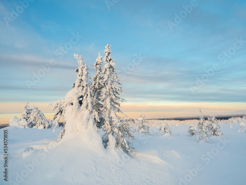 Beautiful Arctic sunset. Scenic colorful sky at dawn. Snow-covered slope of the polar hill in the winter early in the morning. Winter polaris landscape. Dawn of winter silence.