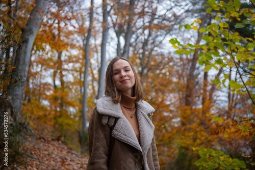 A portrait of a sweet girl with short hair enjoying the autumn weather  playing with colourful autumn leaves  having fun in autumn leaves © Jakub