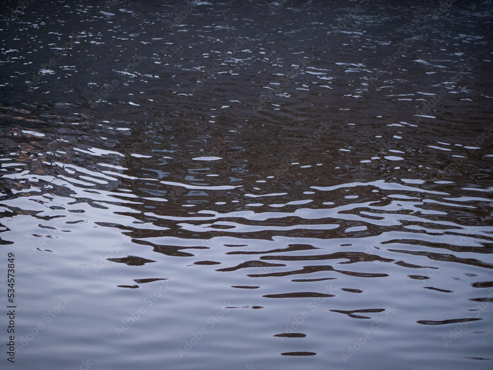 Obraz premium Ondes et reflets dans l'eau brune de la rivière