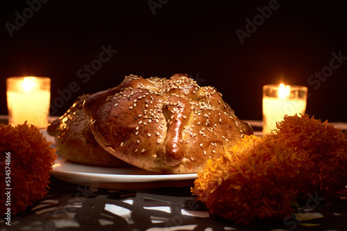 Bread of the dead with cempasuchil flowers, candles around and placed with confetti with dia de muertos shapes photo