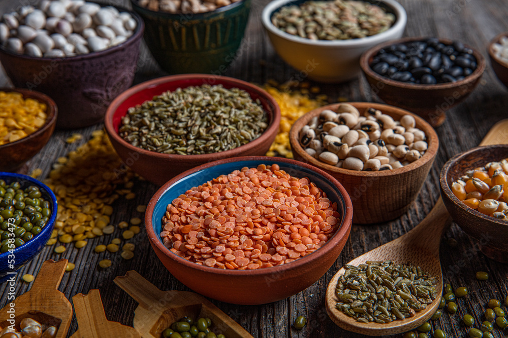 Vegan protein source.Various assortment of legumes, lentils, chickpea and beans assortment in different bowls on wooden table. Top view.