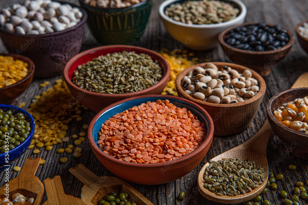 Vegan protein source.Various assortment of legumes, lentils, chickpea and beans assortment in different bowls on wooden table. Top view. Vegan protein source.Various assortment of legumes, lentils, chickpea and beans assortment in different bowls on wooden table. Top view.