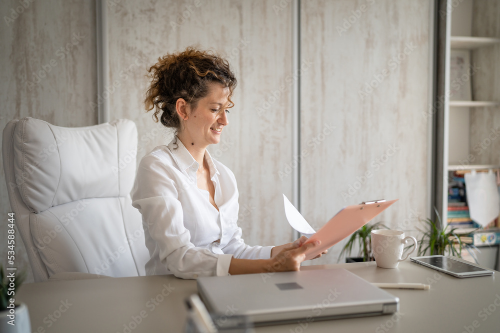 One young business woman working in the office holding clipboard