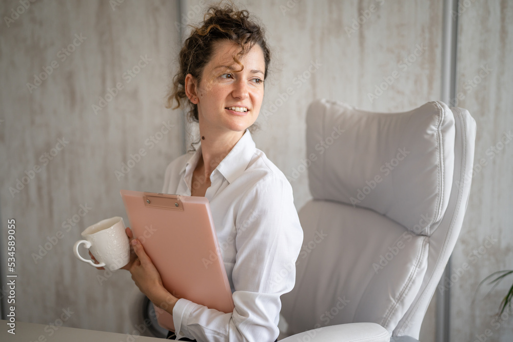 One young business woman working in the office holding clipboard One young business woman working in the office holding clipboard