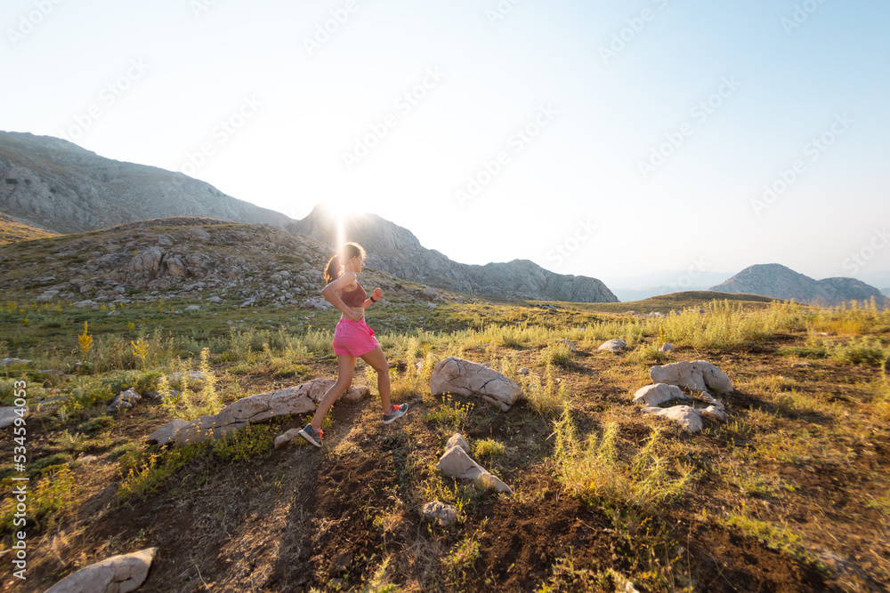 Runner woman running through beautiful mountains