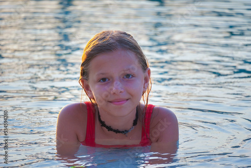 teenage girl with dark hair lies in the pool and smiles