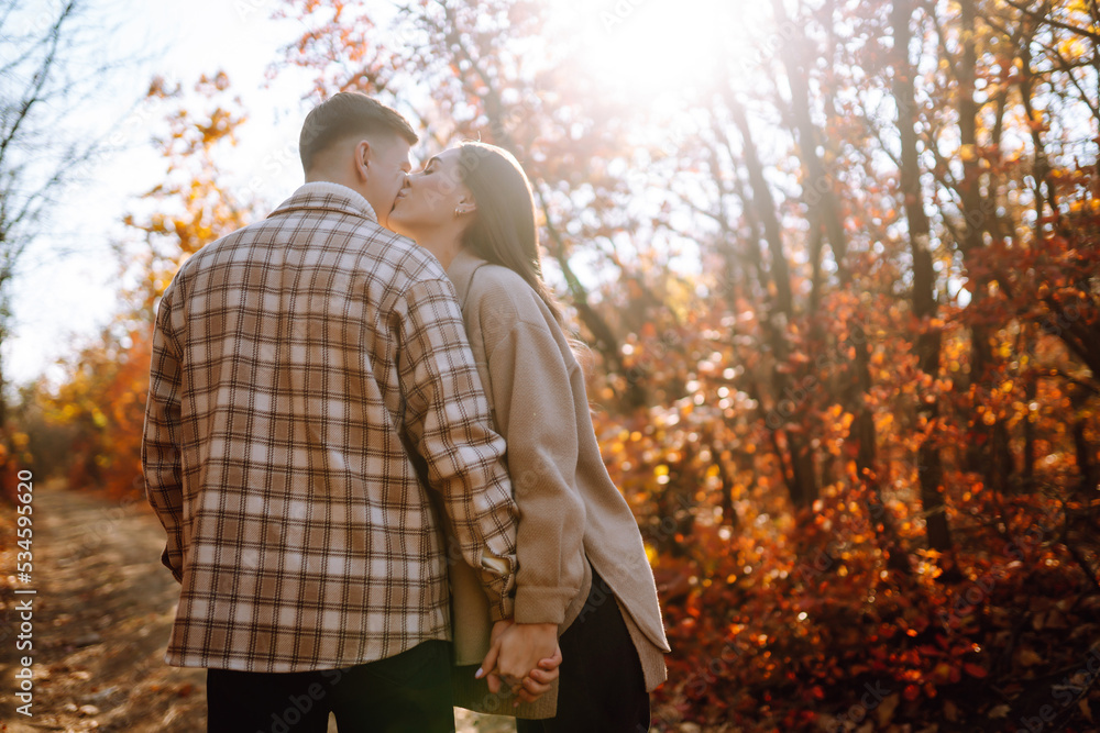 Happy couple in love newlyweds in casual clothes travel together, hike and walk in the autumn forest in nature.