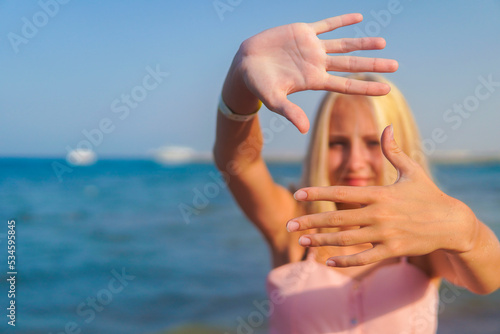 teenage girl blonde with glasses to keep her hands in the sand by the sea
