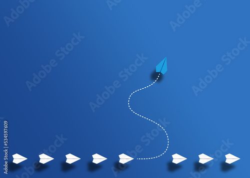 paper planes in a row and one paper glider going in different direction above blue background, breaking new ground and stepping out of the line concept
