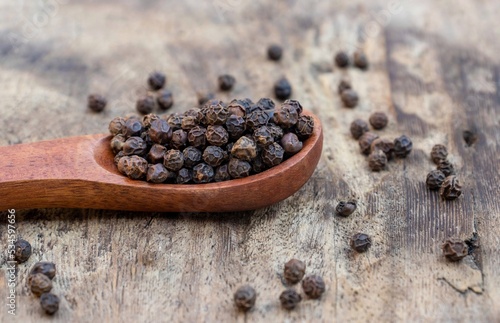 Black Pepper or Piper Nigrum Seed in a Wooden Spoon Isolated Wooden Background in Horizontal Orientation