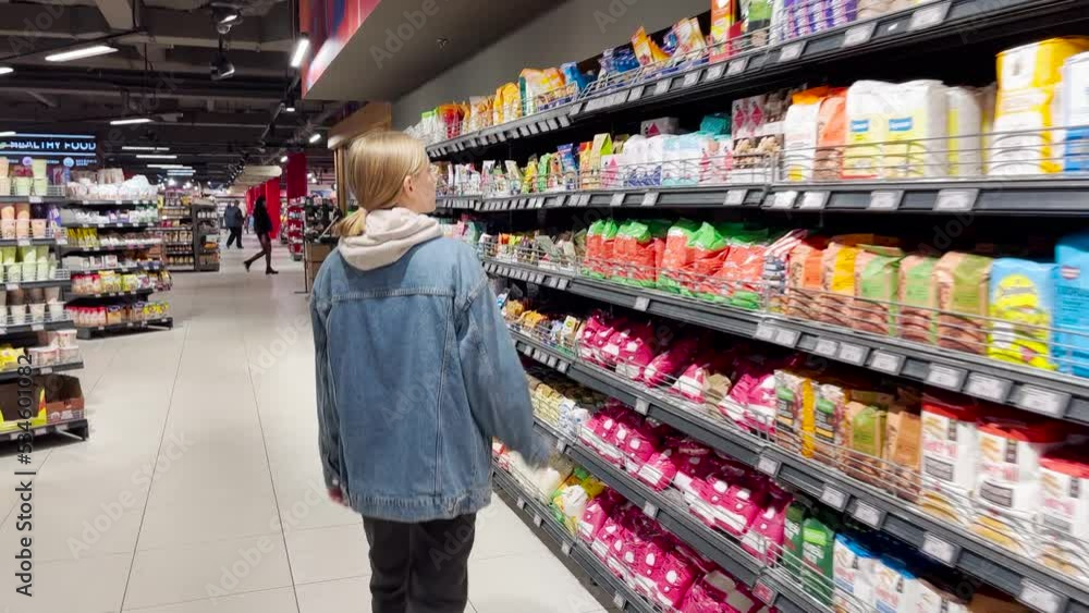 a woman chooses a product on the shelves of a supermarket a woman chooses a product on the shelves of a supermarket
