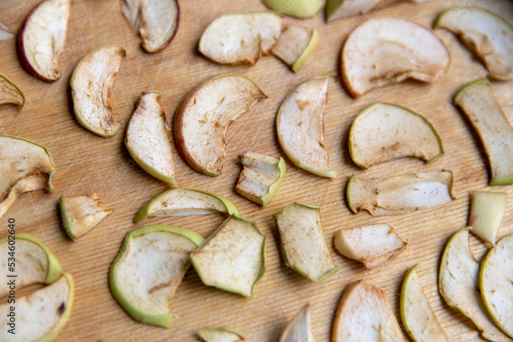 Fototapeta premium Sliced apple slices are laid out on a cutting board and dried in the kitchen. Dried apples