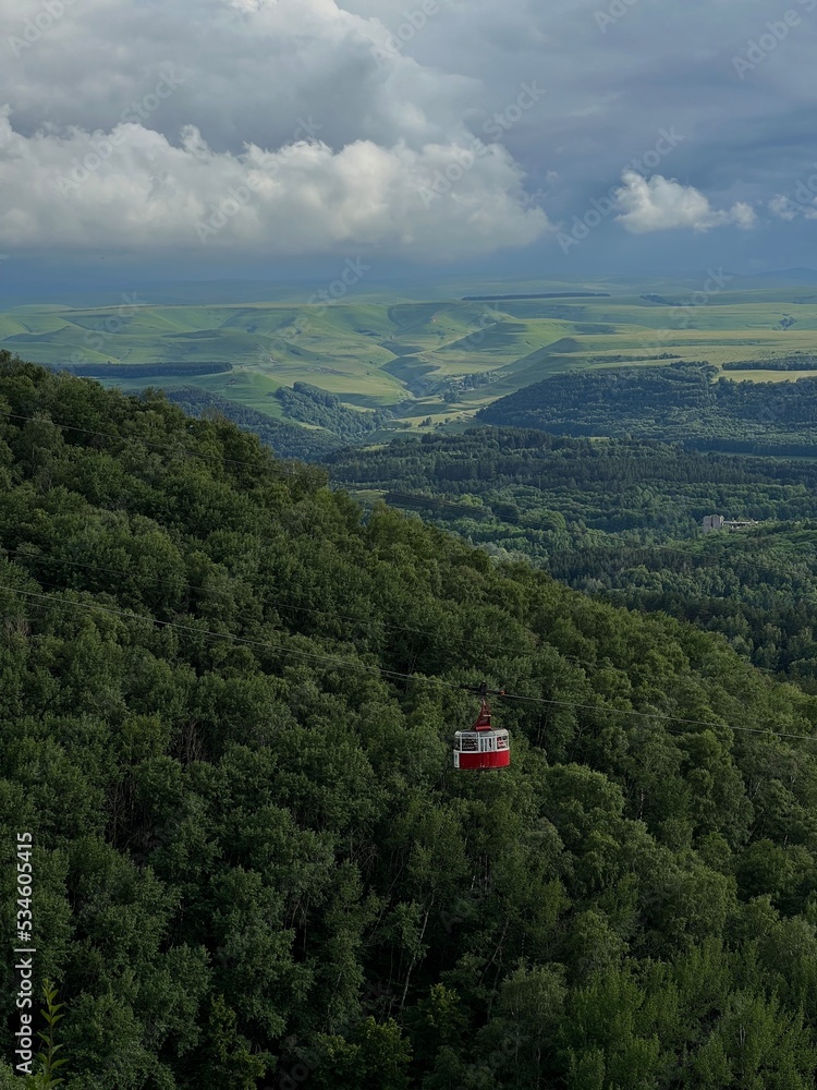 photo of a red funicular on the background of green mountains, a beautiful view of the mountains