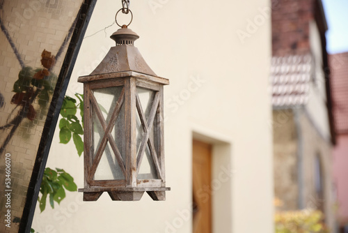 Old lantern hangs on the wall of the house 