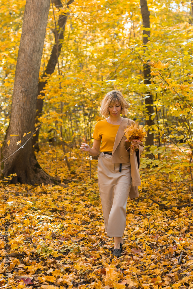 Walking woman on a fall day in the beautiful autumn park. Season and loneliness concept Walking woman on a fall day in the beautiful autumn park. Season and loneliness concept