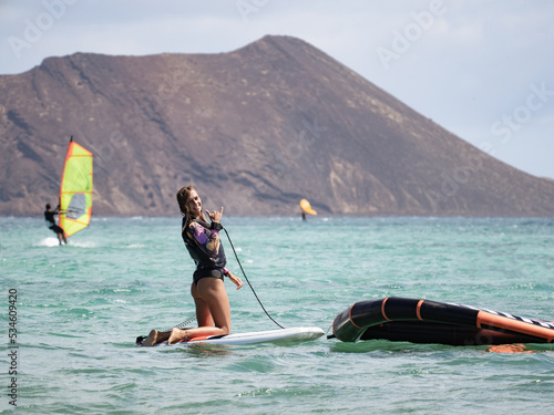 Happy surfer young woman doing the shaka. She is practicing wingfoil surfing in the atlantic ocean. photo