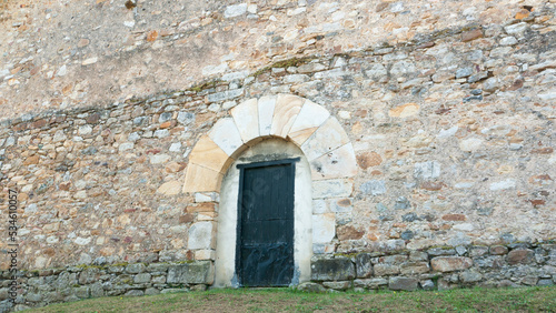 Puerta de madera en arco de piedra en fachada de casa rural