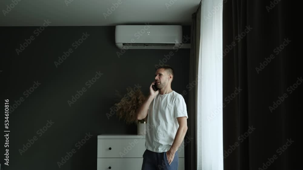 Man in home clothes calls on mobile phone in room with air conditioner. Man in home clothes calls on mobile phone in room with air conditioner.