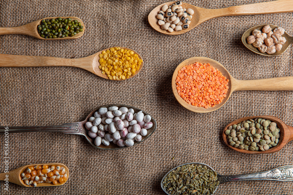 Vegan protein source. Various kinds of legumes, lentils, chickpeas and beans in different spoons on wooden table. top view. Vegan protein source. Various kinds of legumes, lentils, chickpeas and beans in different spoons on wooden table. top view.