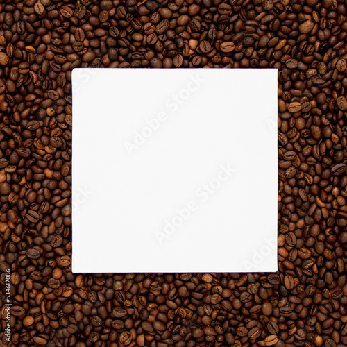 White square card on brown roasted coffee beans. Minimal concept of copy space.