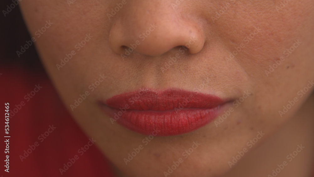 Fototapeta premium CLOSE UP: Detailed shot of young female lips after applying shiny red lip gloss