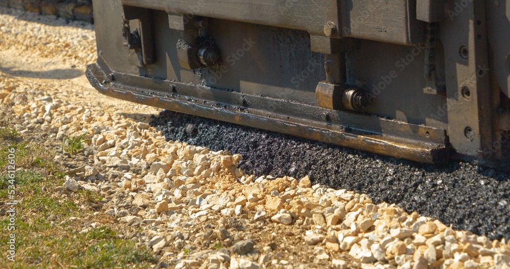 CLOSE UP: Laying black asphalt over crushed rocks with asphalt paver machine CLOSE UP: Laying black asphalt over crushed rocks with asphalt paver machine