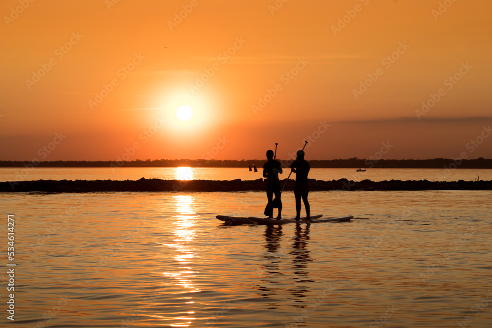 Silhouette of a man with a paddle on a SUP surfboard