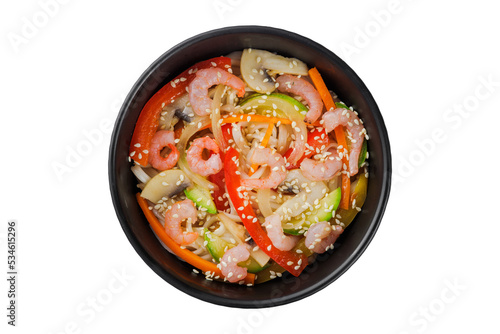 Noodles wok, with vegetables, herbs and sesame. In a black round plate. On a white background.